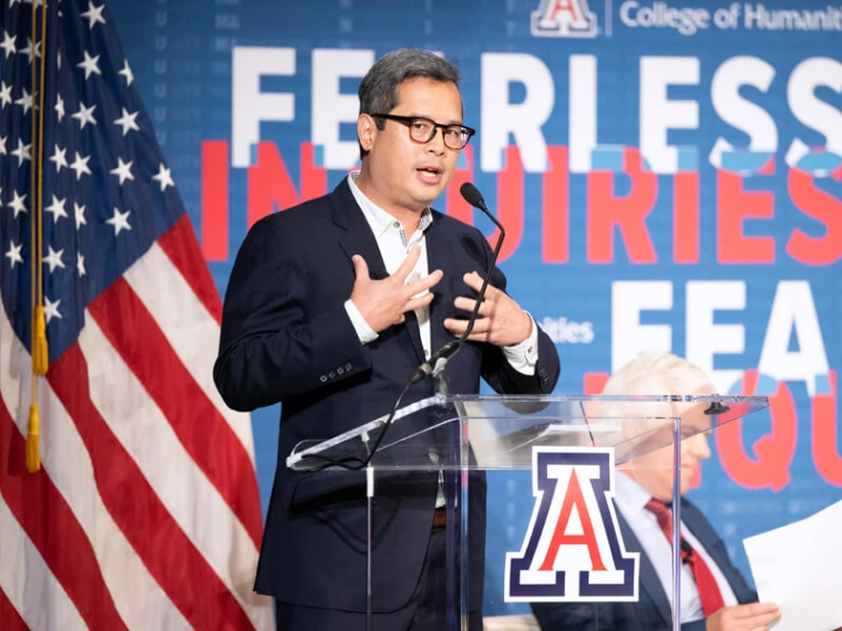 Speaker on stage at a podium with USA flag behind him
